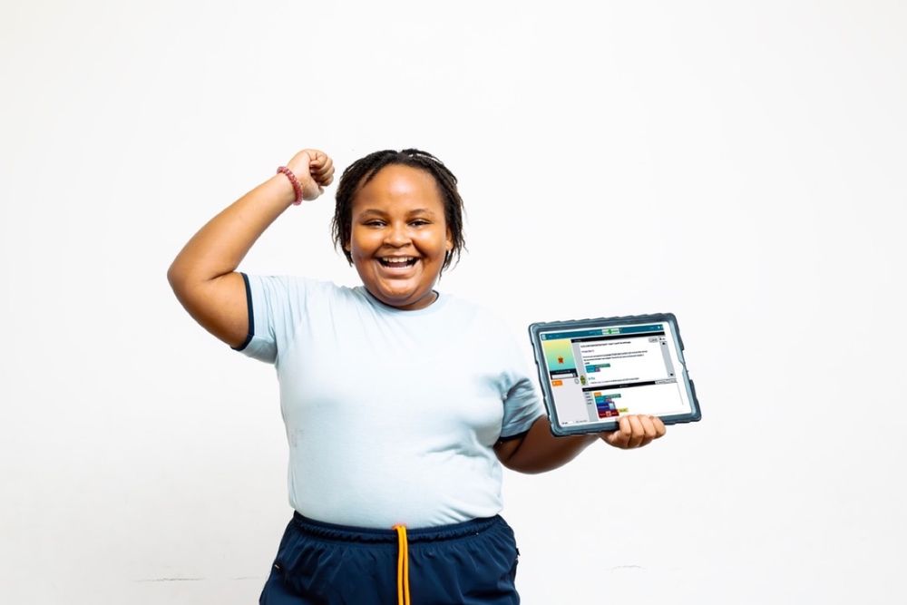 A Kodeuni student celebrating, holding up the project she built